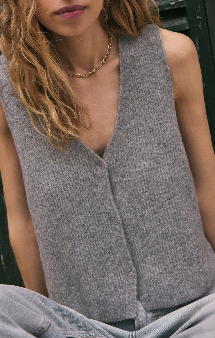 Person wearing a gray sleeveless top with a blurred background