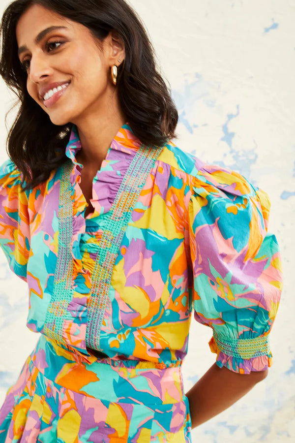 Woman wearing vibrant abstract puff sleeve blouse with v-neck detail