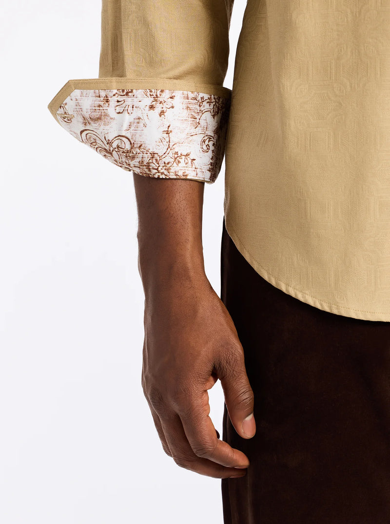 Close-up of a person wearing a beige shirt with floral cuffs on a white background
