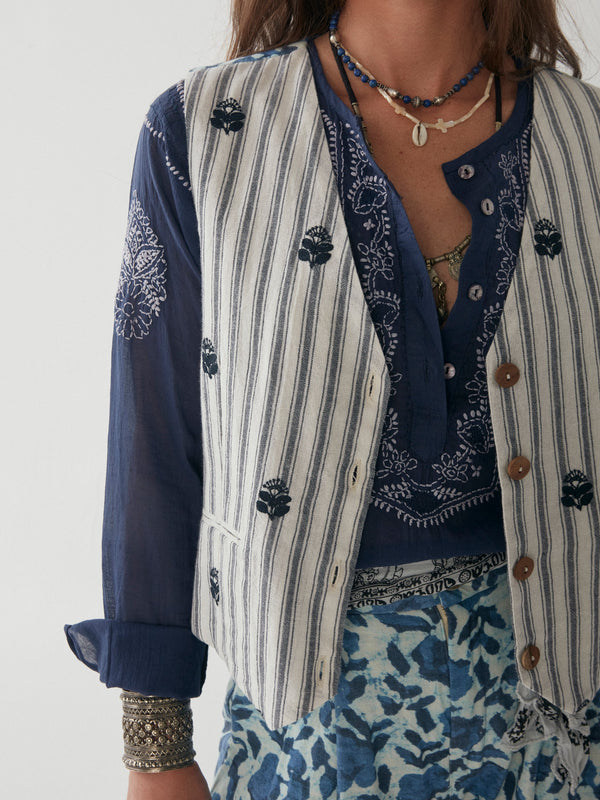 Woman wearing blue and white stripe vest with floral embroidery in navy blue