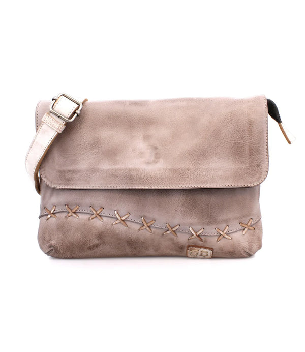 Beige color rectangle purse with flap, x stitch detail on bottom, and crossbody strap