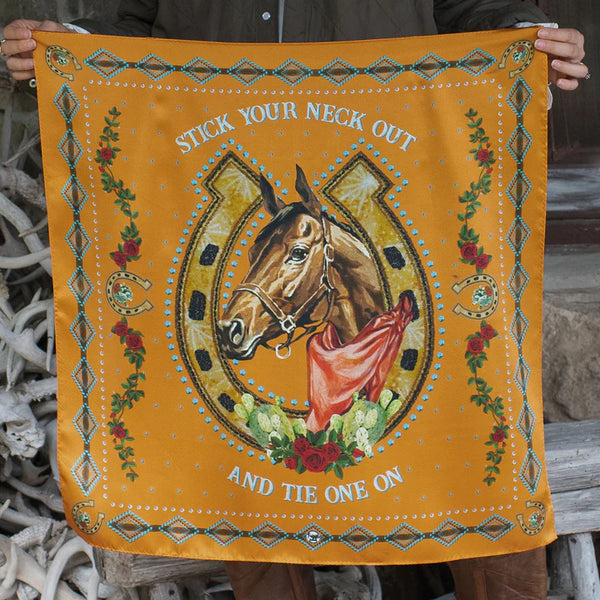 Orange wild rag with horse head framed by horse shoe with words "Stick our neck out and tie one on" around the image