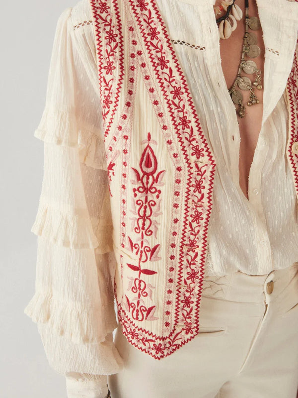 Woman wearing cream and red embroidery vest with red and white stripe on the back