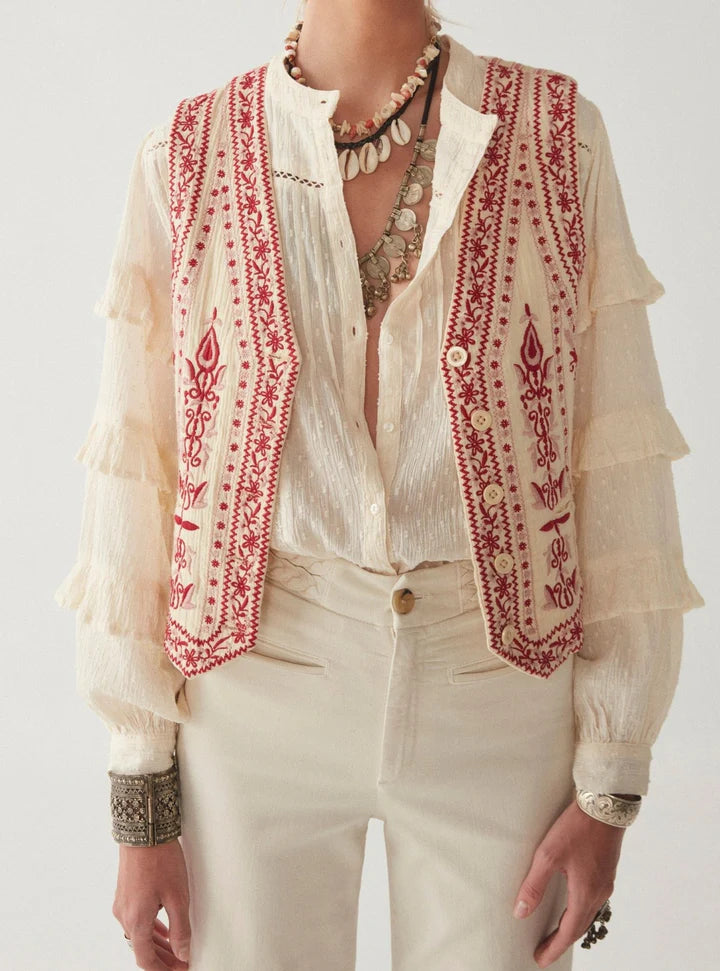 Woman wearing cream and red embroidery vest with red and white stripe on the back