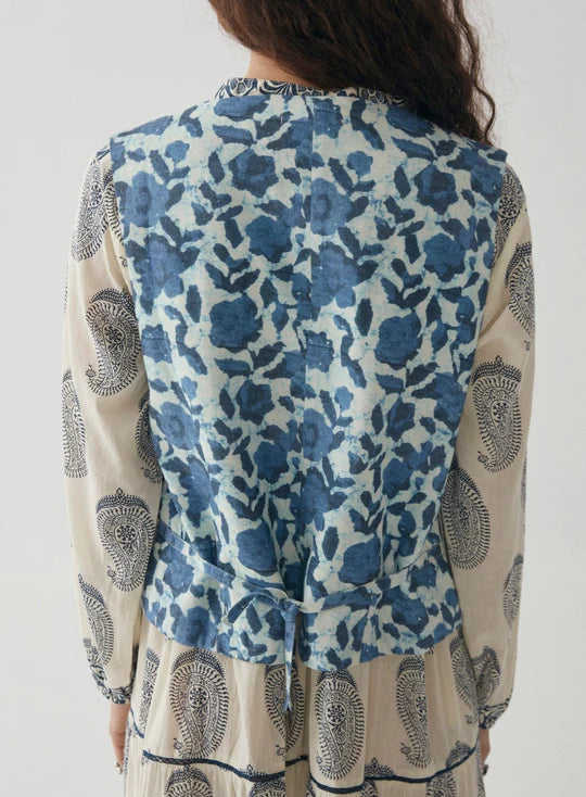 Woman wearing blue and white stripe vest with floral embroidery in navy blue with floral pattern on the back