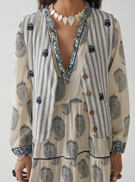Woman wearing blue and white stripe vest with floral embroidery in navy blue with floral pattern on the back