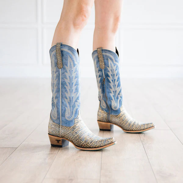 Blue and silver cowboy boots on a light wooden floor.