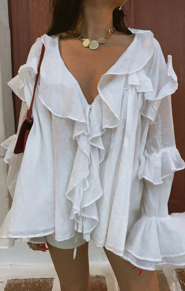 White ruffled blouse worn by a person with a blurred background