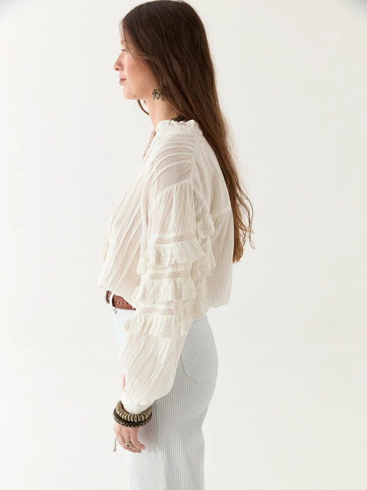 Woman wearing a white blouse with long sleeves against a plain background