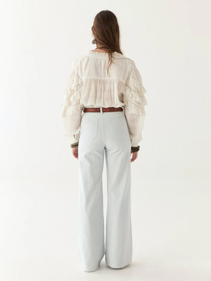 Person wearing a white blouse and light gray pants on a white background