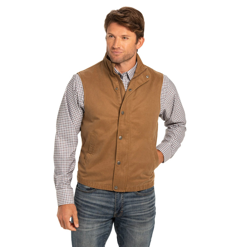 Man wearing a brown vest over a checkered shirt on a white background