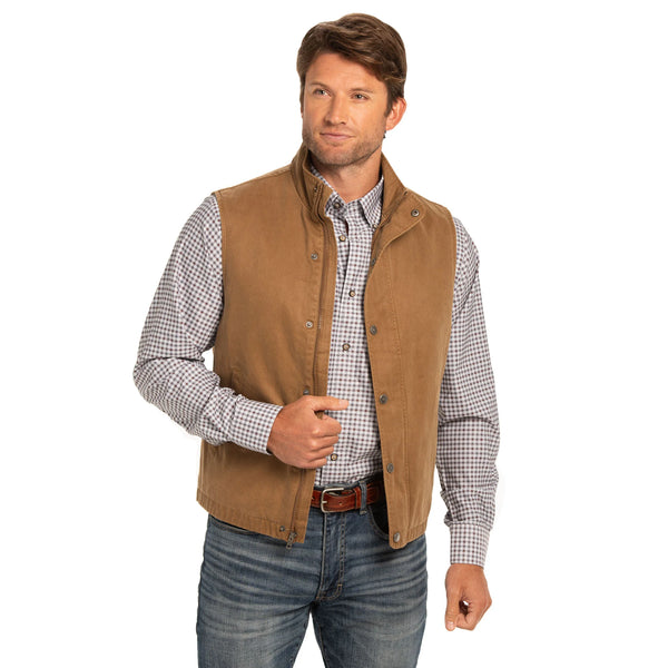 Man wearing a brown vest over a checkered shirt on a white background