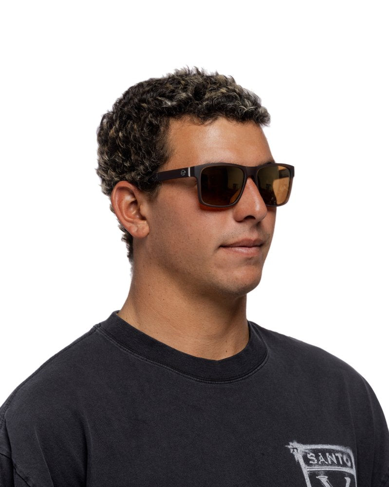 Man wearing sunglasses and a black shirt with a logo on a white background