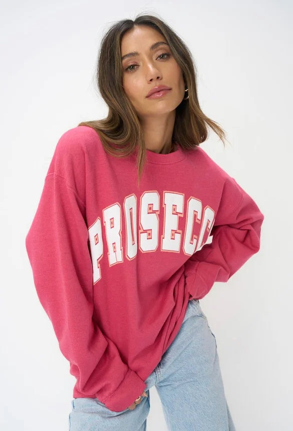 Woman wearing raspberry colored sweatshirt with word "PROSECCO" in all caps on front