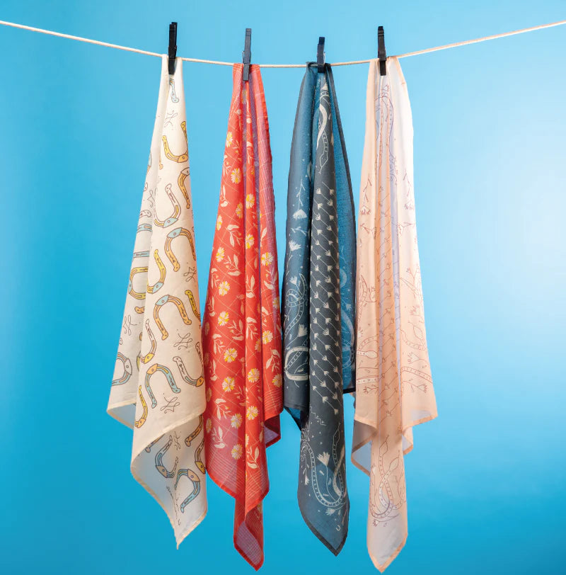 Five patterned scarves hanging on a clothesline against a blue background