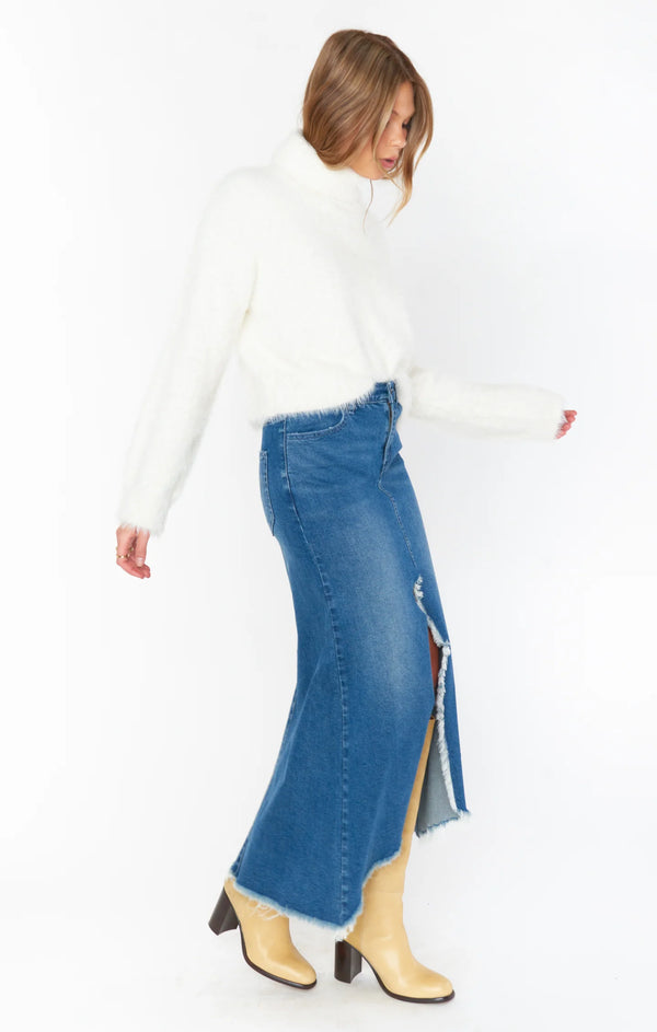 Woman wearing denim maxi skirt with fuzzy white sweater and fall boots