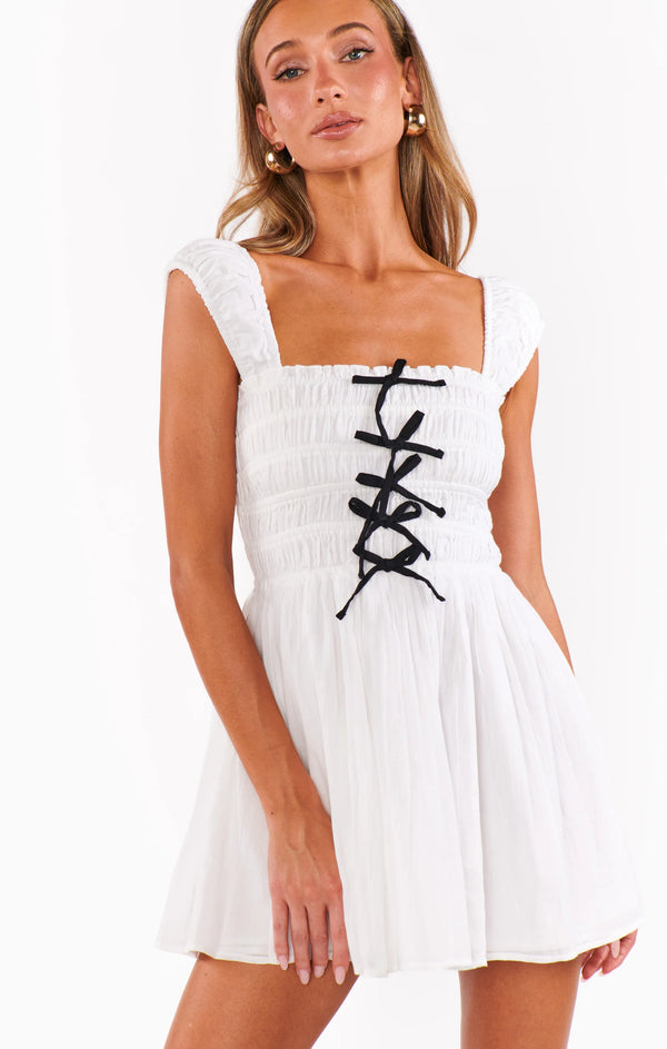 Woman wearing a white dress with black lace details on a white background