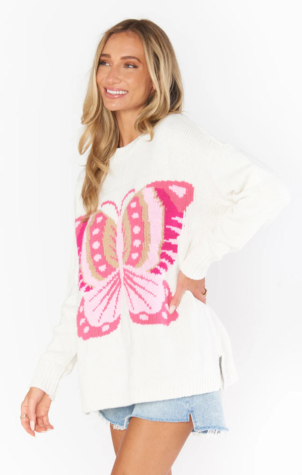 Woman wearing white long sleeve sweater with giant pink butterfly on the front