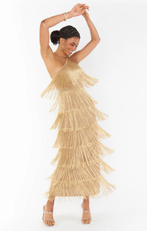 Woman wearing gold maxi halter dress with fringe tiers throughout  