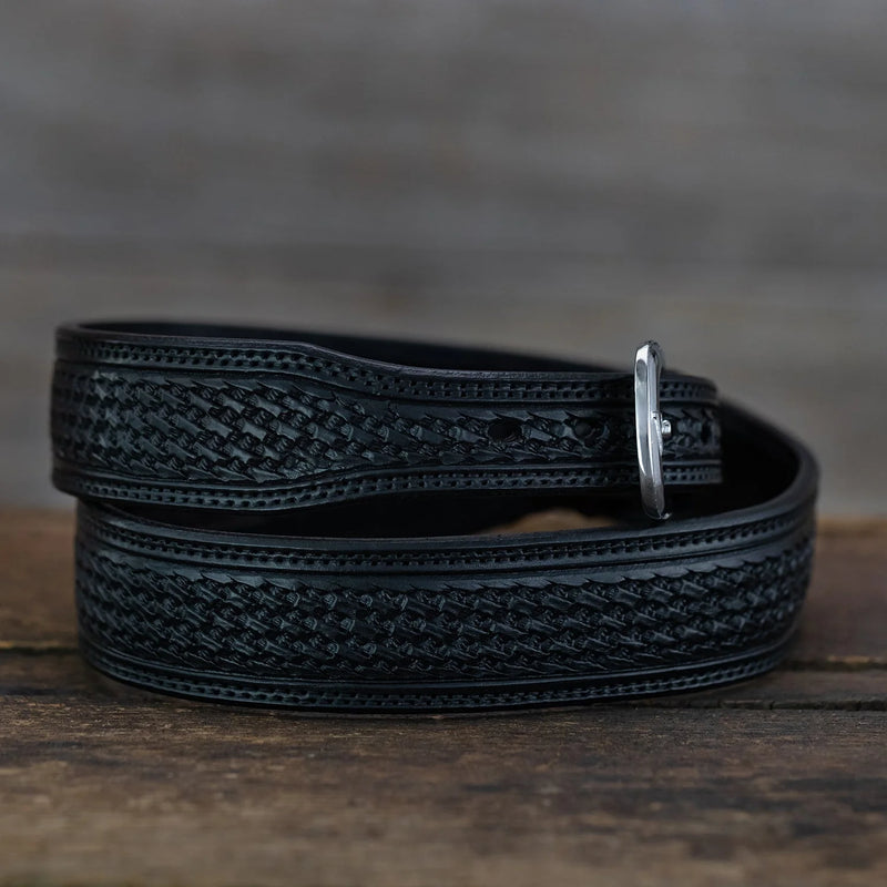 Black leather belt with intricate pattern on a wooden surface