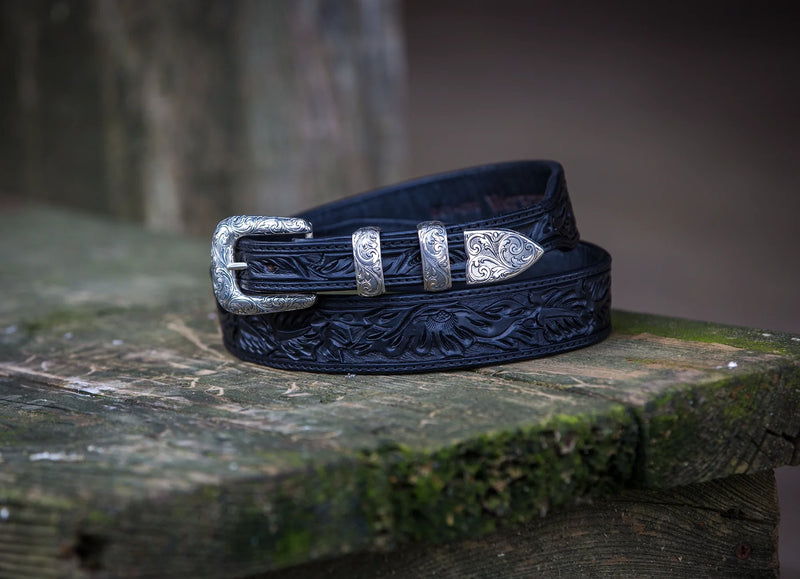 Black leather belt with leaf tooling detail and silver belt buckle with "v" on it