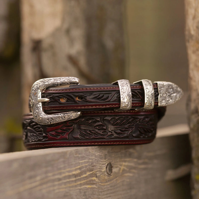 Decorative leather belt with silver buckle on a wooden surface