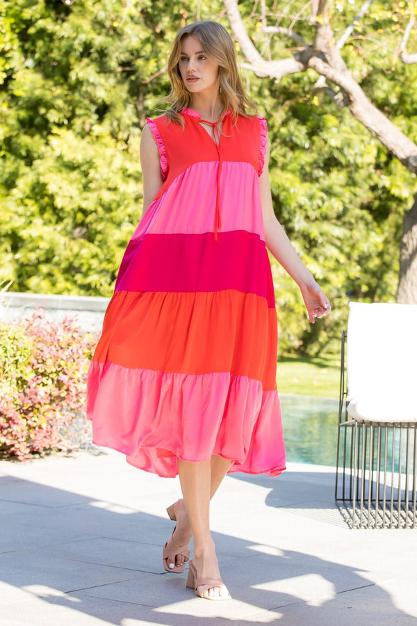 Woman wearing pink and red midi length tiered dress with v-neck and tie on neck