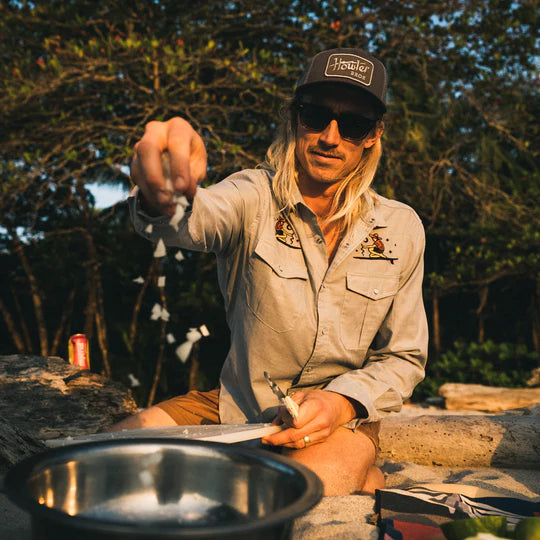 A man cooking outdoors wearing HOWLER ELECTRIC CAP